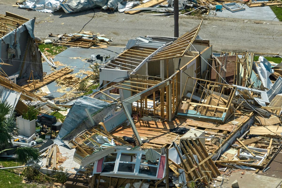 Devastated neighborhood showing destroyed homes, scattered debris, and exposed structures after a severe storm or hurricane.