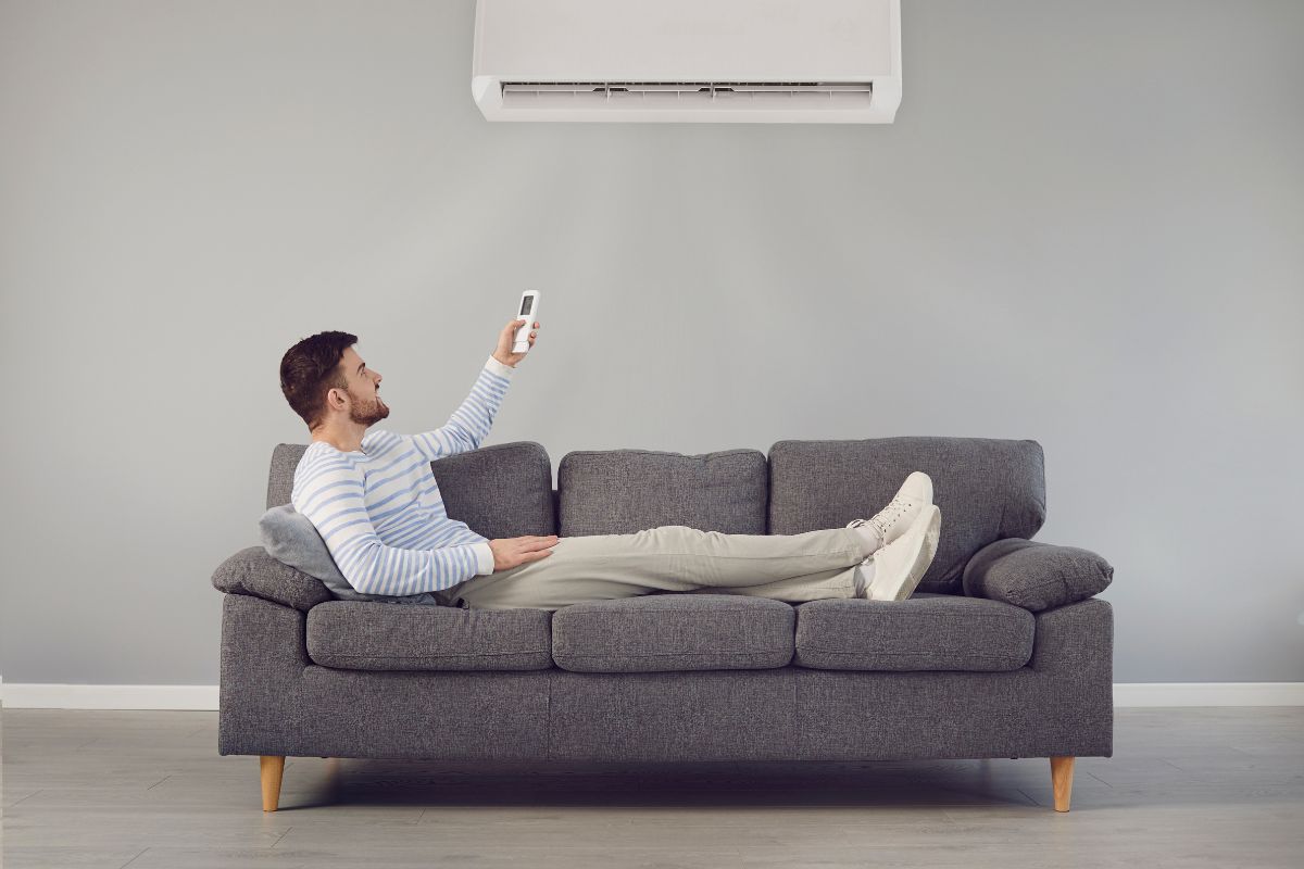 Man sitting on a couch, holding a remote control, relaxed and watching television.